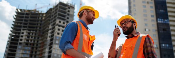 Contractor speaking on walkie-talkie with co-worker near by